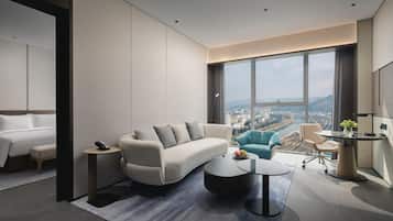 Une chambre d’hôtel moderne dotée d’une grande fenêtre, d’un canapé, d’un bureau et d’un lit.