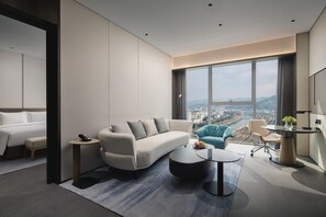 A modern hotel room with a large window, a sofa, a desk, and a bed. - Crowne Plaza Shangluo (Shanglou)