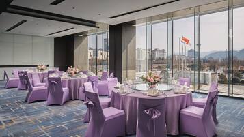 A conference room with round tables, purple chairs, and a city view through large windows.