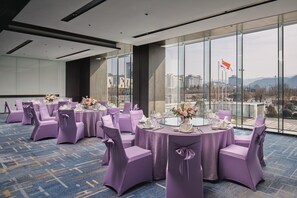 A conference room with round tables, purple chairs, and a city view through large windows. - Crowne Plaza Shangluo (Shanglou)