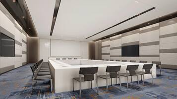 A conference room with a long table, chairs, a whiteboard, and a carpeted floor.