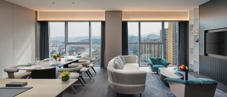 A modern living room with a dining area, large windows, and a city view.