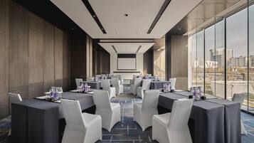 A conference room with tables and chairs, large windows, and a city view.