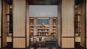 Eine moderne Hotelhalle mit einer zentralen Rezeption, Marmorböden und Holzvertäfelung.