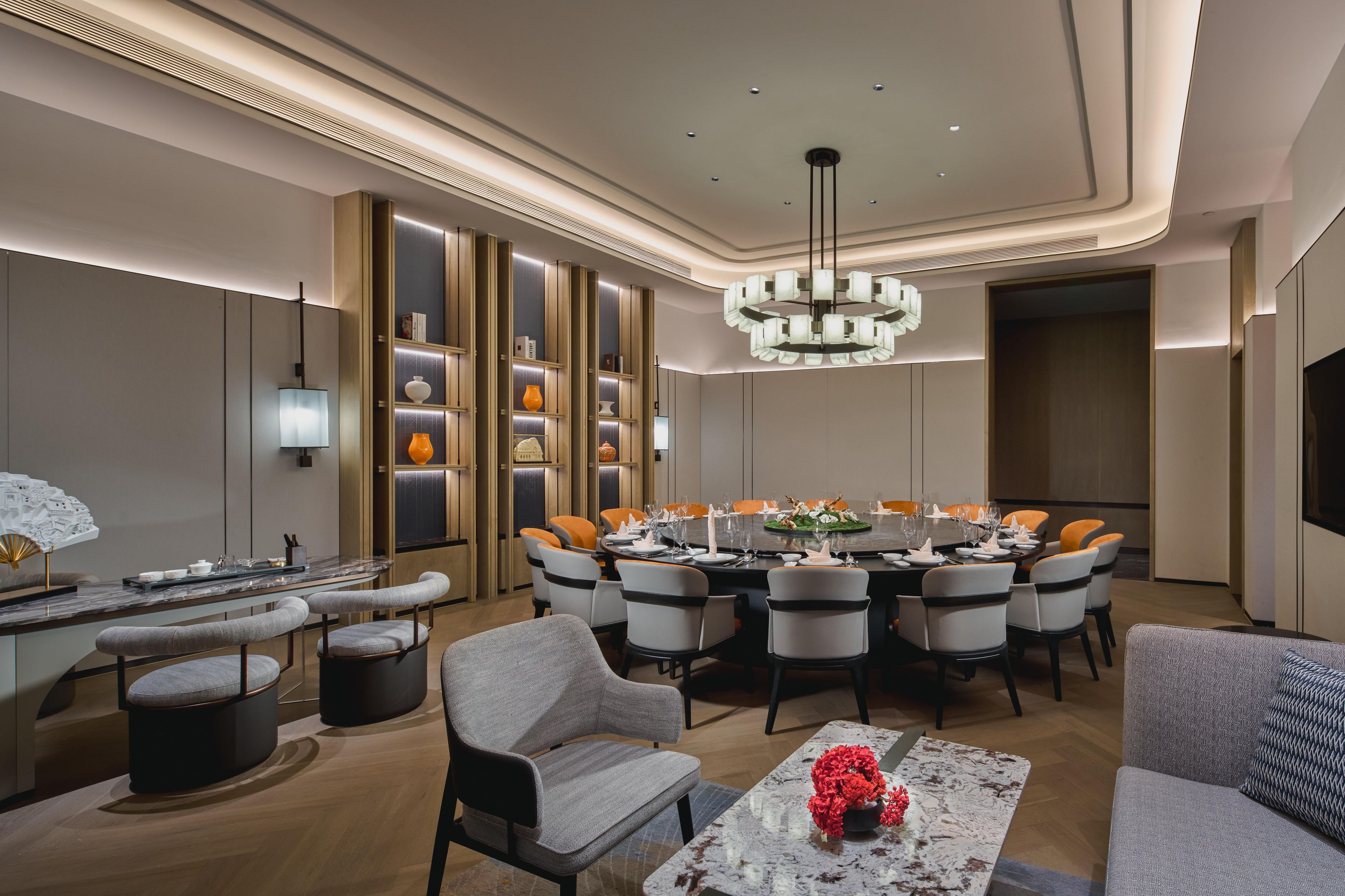 A modern dining area with a round table, multiple chairs, and a chandelier.
