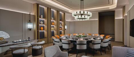 A modern dining area with a round table, multiple chairs, and a chandelier.