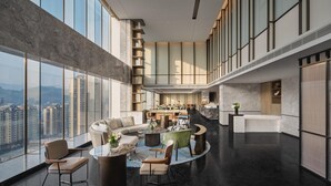 A spacious lobby with a curved seating area, a bar, and a view of high-rise buildings. - Crowne Plaza Shangluo (Shanglou)