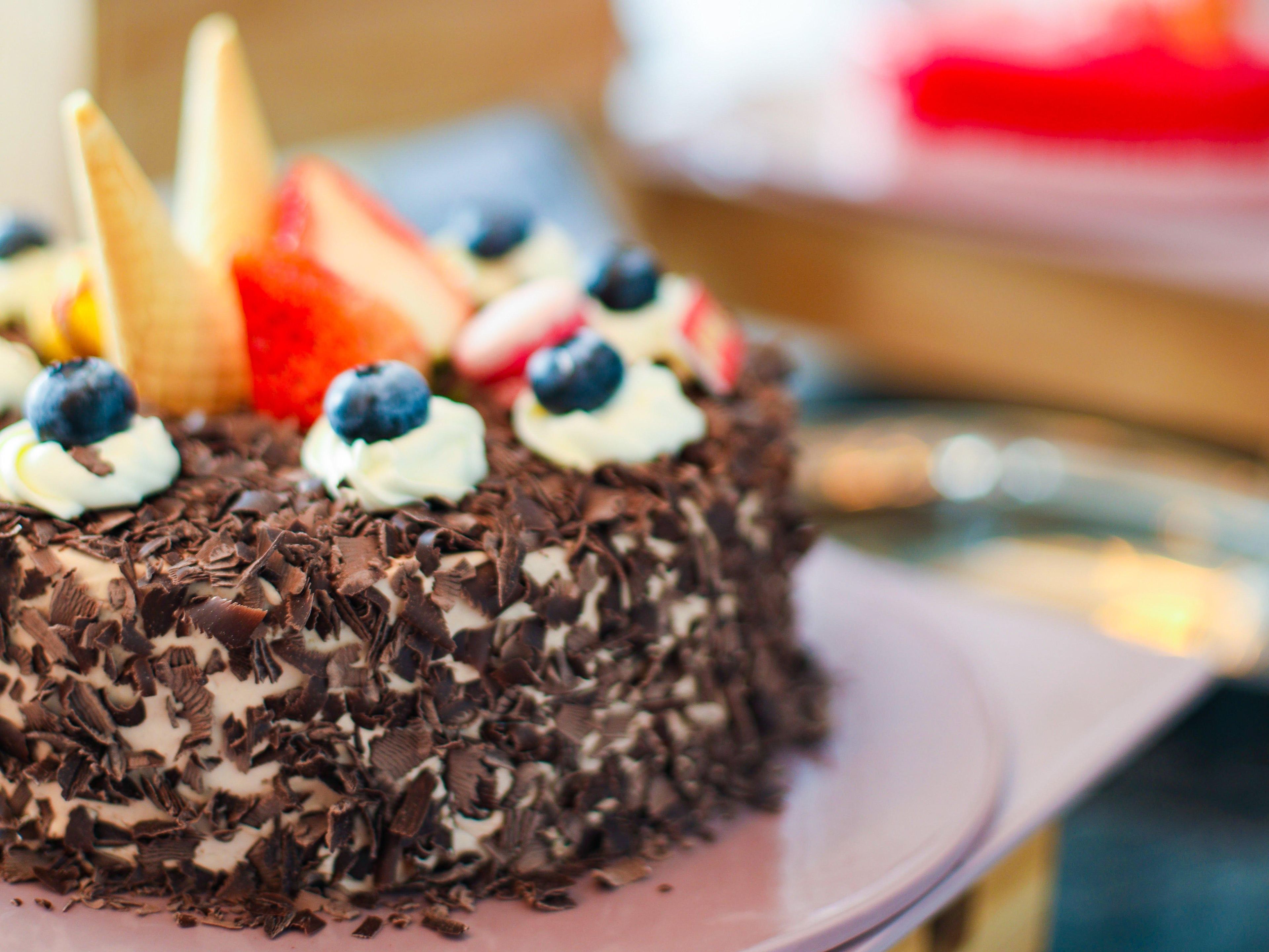 A chocolate cake with whipped cream and blueberries on a pink plate.