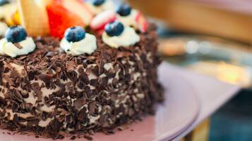 A chocolate cake with whipped cream and blueberries on a pink plate.