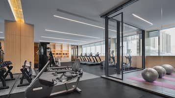 A modern gym with exercise equipment, a weight bench, and a wall with a water bottle shelf.
