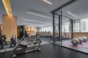 A modern gym with exercise equipment, a weight bench, and a wall with a water bottle shelf. - Crowne Plaza Shangluo (Shanglou)
