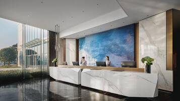 A modern reception area with a marble reception desk, two receptionists, and a large digital display wall.