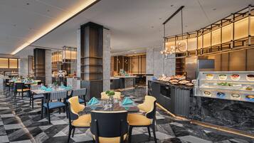 A modern restaurant with marble flooring, high ceilings, and a buffet area with various dishes.