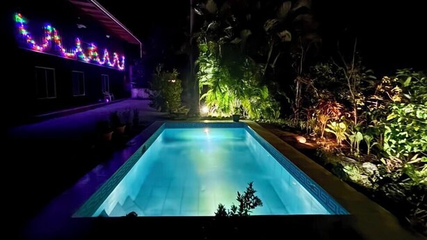 A swimming pool at night with colorful lights on the adjacent building. - Charming lodge in beautiful Playa Samara with WiFi (Playa Samara Guanacaste Province)