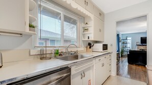 A modern kitchen with white cabinets, a stainless steel dishwasher, a double sink, and a microwave. - Colorado Bay A (Colorado Springs)