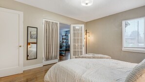 A bedroom with a large bed, a door leading to a hallway, and a window with blinds. - Colorado Bay A (Colorado Springs)