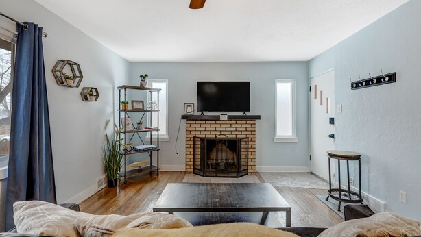 A living room with a brick fireplace, a television, and a coffee table. - Colorado Bay A (Colorado Springs)