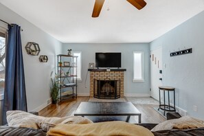 A living room with a brick fireplace, a television, and a coffee table. - Colorado Bay A (Colorado Springs)
