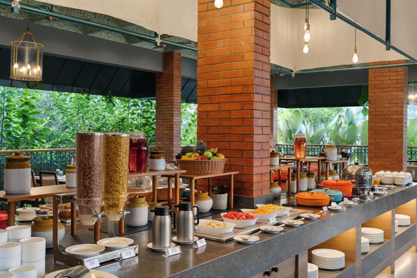 Een buffetopstelling met diverse gerechten, serveerbestek en decoratieve elementen.