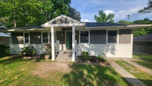 A single-story house with a front porch, a green door, and a mailbox.