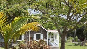 A wooden cabin with a porch, surrounded by lush greenery and a well-maintained lawn.