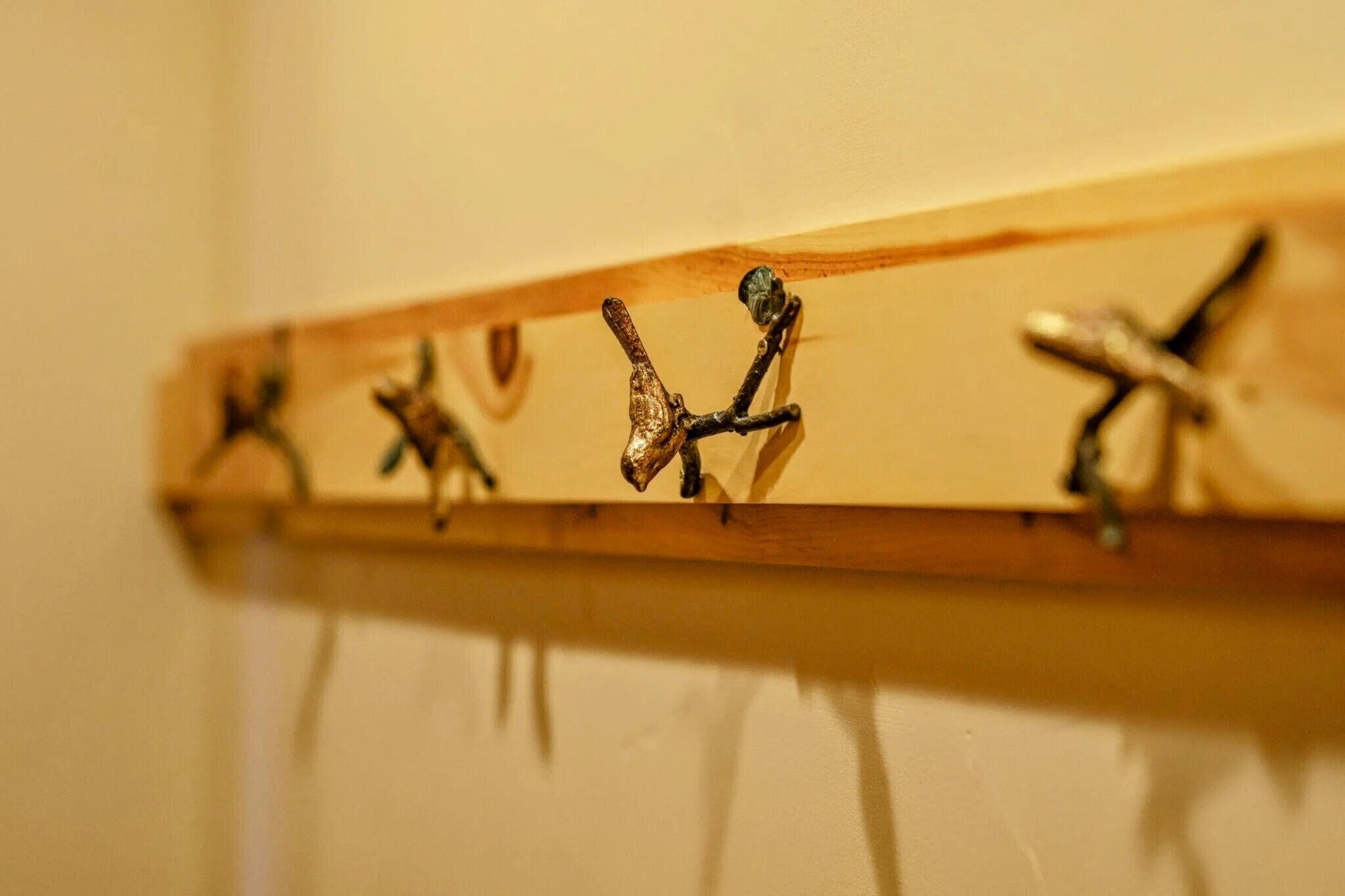 A wooden coat rack with four metal hooks.