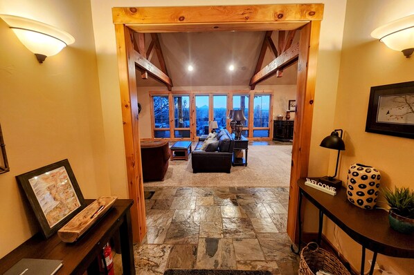 Un espacio de sala amplio con techo alto, ventanas grandes y una acogedora disposición de asientos.