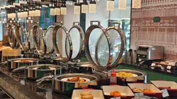 A buffet setup with multiple food stations, including a variety of dishes in containers and a selection of beverages.