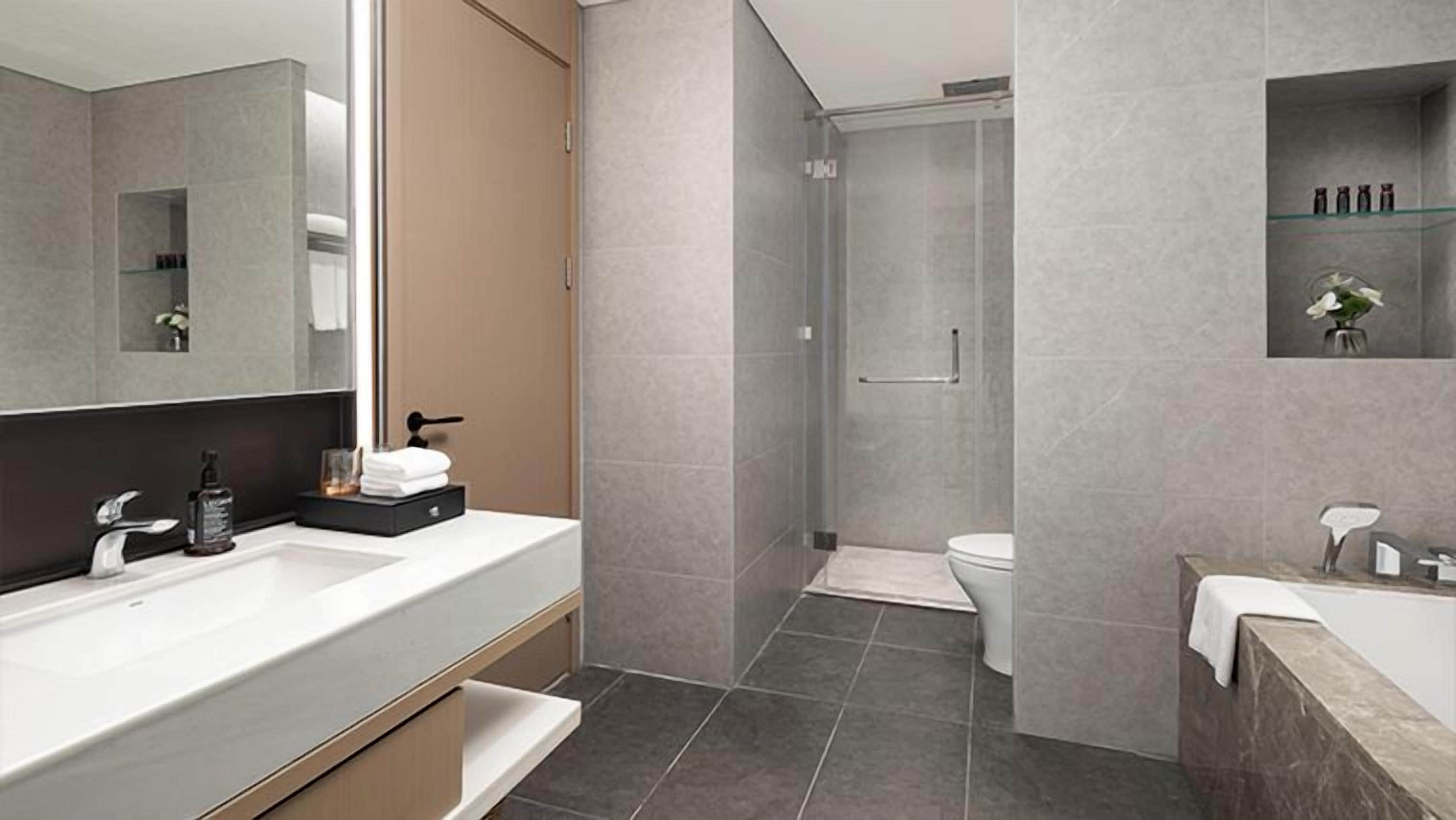 A modern bathroom with a large mirror, a sink, a toilet, and a shower area.