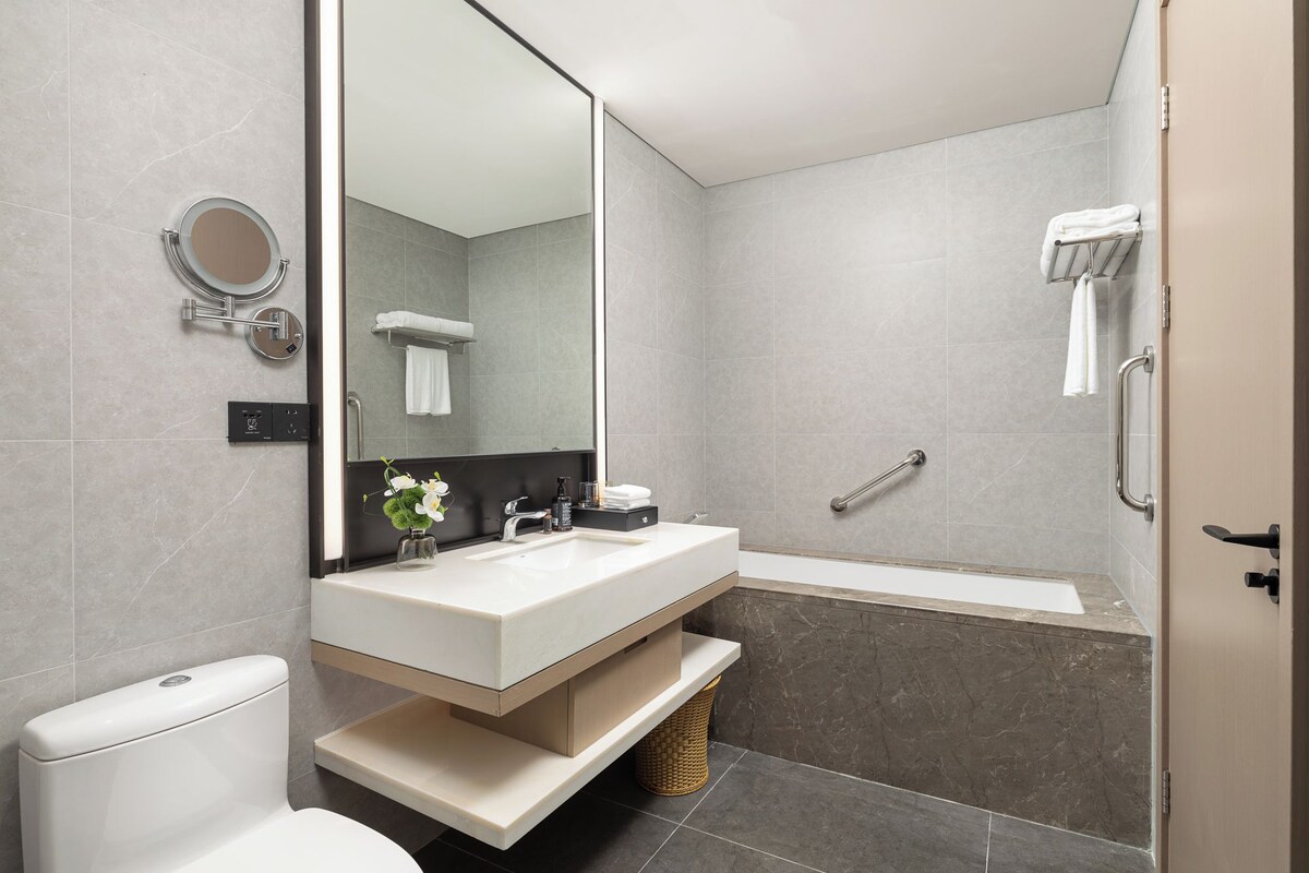 Ein modernes Badezimmer mit Toilette, Waschbecken, Spiegel und Badewanne.