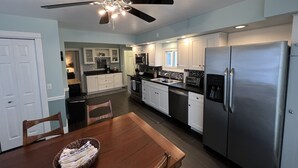 A modern kitchen with white cabinets, stainless steel appliances, and a ceiling fan. - Off season weekly and monthly rates! 700 weekly, 2400 monthly (Muskegon)