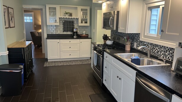 A modern kitchen with white cabinets, a black countertop, and a stainless steel sink. - Off season weekly and monthly rates! 700 weekly, 2400 monthly (Muskegon)