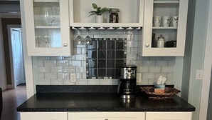 A kitchen with white cabinets, a black countertop, and a tiled backsplash. - Off season weekly and monthly rates! 700 weekly, 2400 monthly (Muskegon)