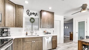 A modern kitchen with wooden cabinets, a stainless steel dishwasher, and a coffee maker. - Cozy on Cactus, Phoenix Escape! Private Pool Oasis, Pet-Friendly, Near Top Attractions! (Phoenix)