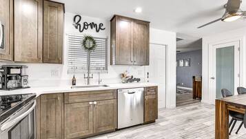 A modern kitchen with wooden cabinets, a stainless steel dishwasher, and a coffee maker.