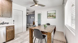 A compact kitchen with wooden cabinets, a dining table with chairs, and a ceiling fan. - Cozy on Cactus, Phoenix Escape! Private Pool Oasis, Pet-Friendly, Near Top Attractions! (Phoenix)