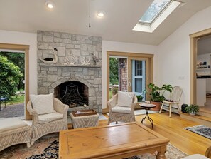 A cozy living room with a stone fireplace, wicker furniture, and a wooden coffee table. - 6 Beachway Road (Sandwich)
