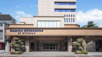A Days Inn by Wyndham hotel entrance with a modern design, large glass doors, and potted plants.