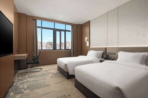 A hotel room with two beds, a TV, a desk, and a large window with a city view. - Days Inn by Wyndham Zhanjiang Economic Development Zone (Zhanjiang)