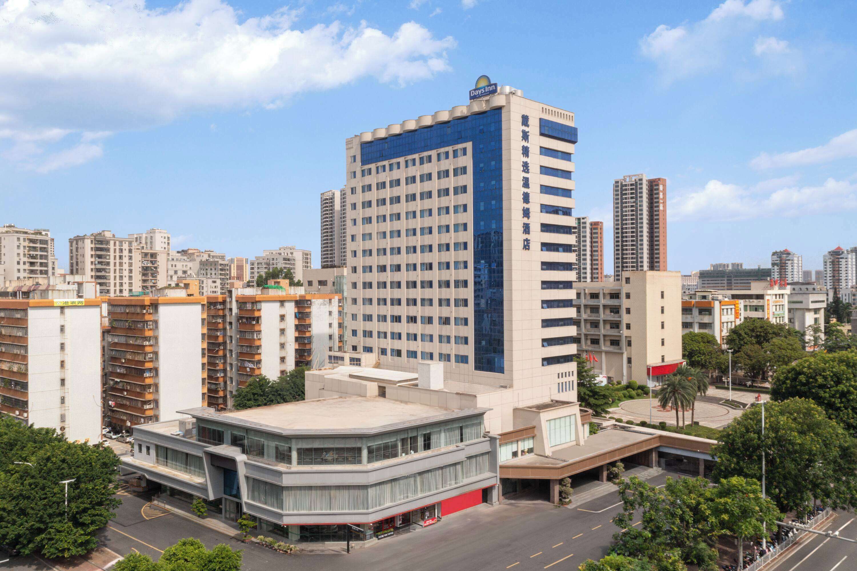 A high-rise hotel with a modern design, featuring a prominent glass facade and a rooftop terrace.