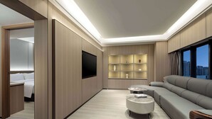 Un salon moderne comprenant un canapé, deux tables basses, un téléviseur à écran plat et des étagères intégrées.