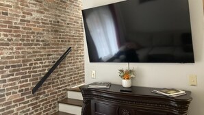 Een bakstenen muur, een trap en een flatscreen televisie die aan de muur is bevestigd.