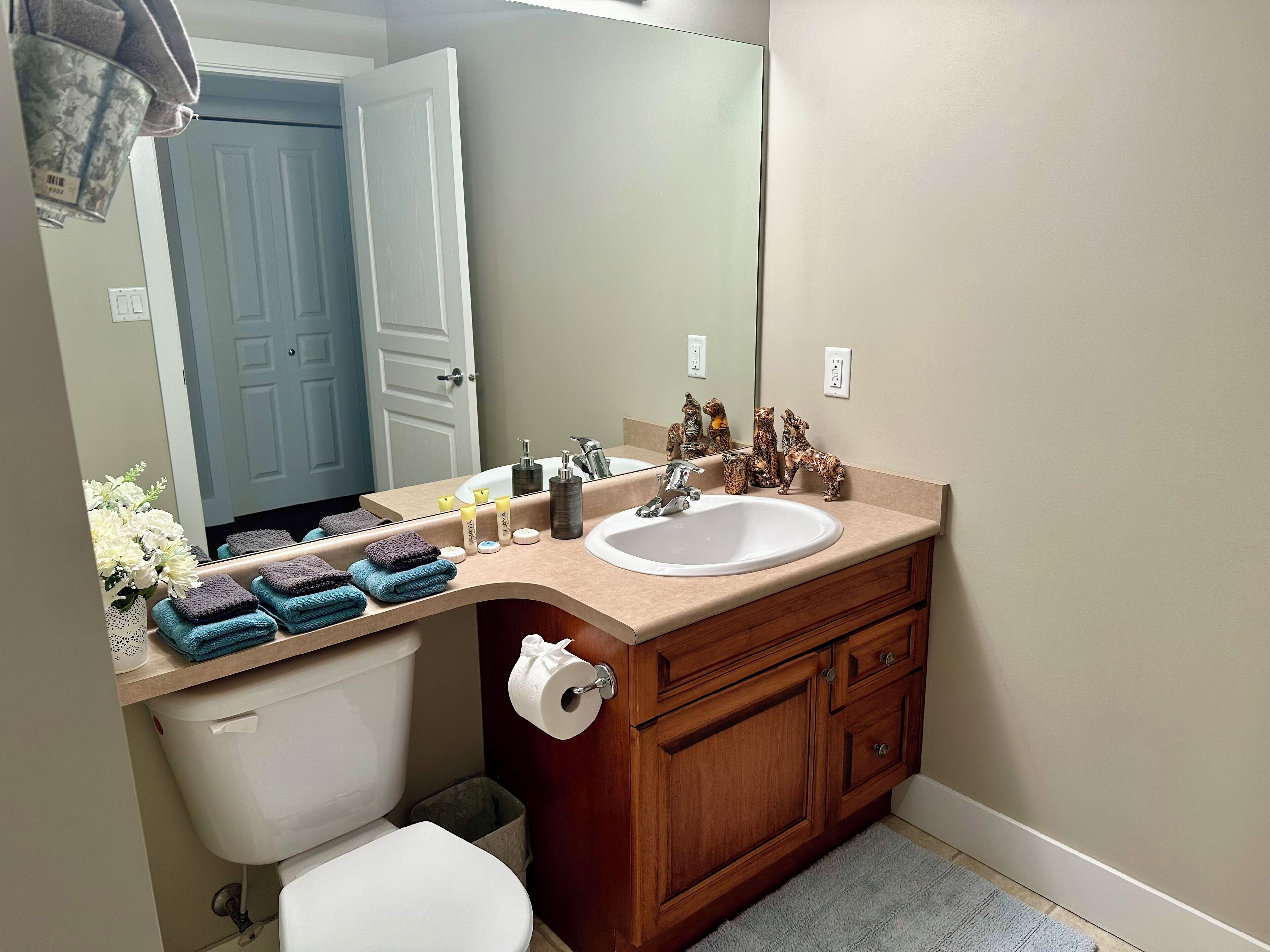 A bathroom with a toilet, sink, vanity, and a mirror.