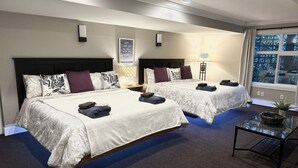 A hotel room with two beds, a glass coffee table, and a view of trees through the window. - Charming Mill Bay 2 Br Suite (Mill Bay)