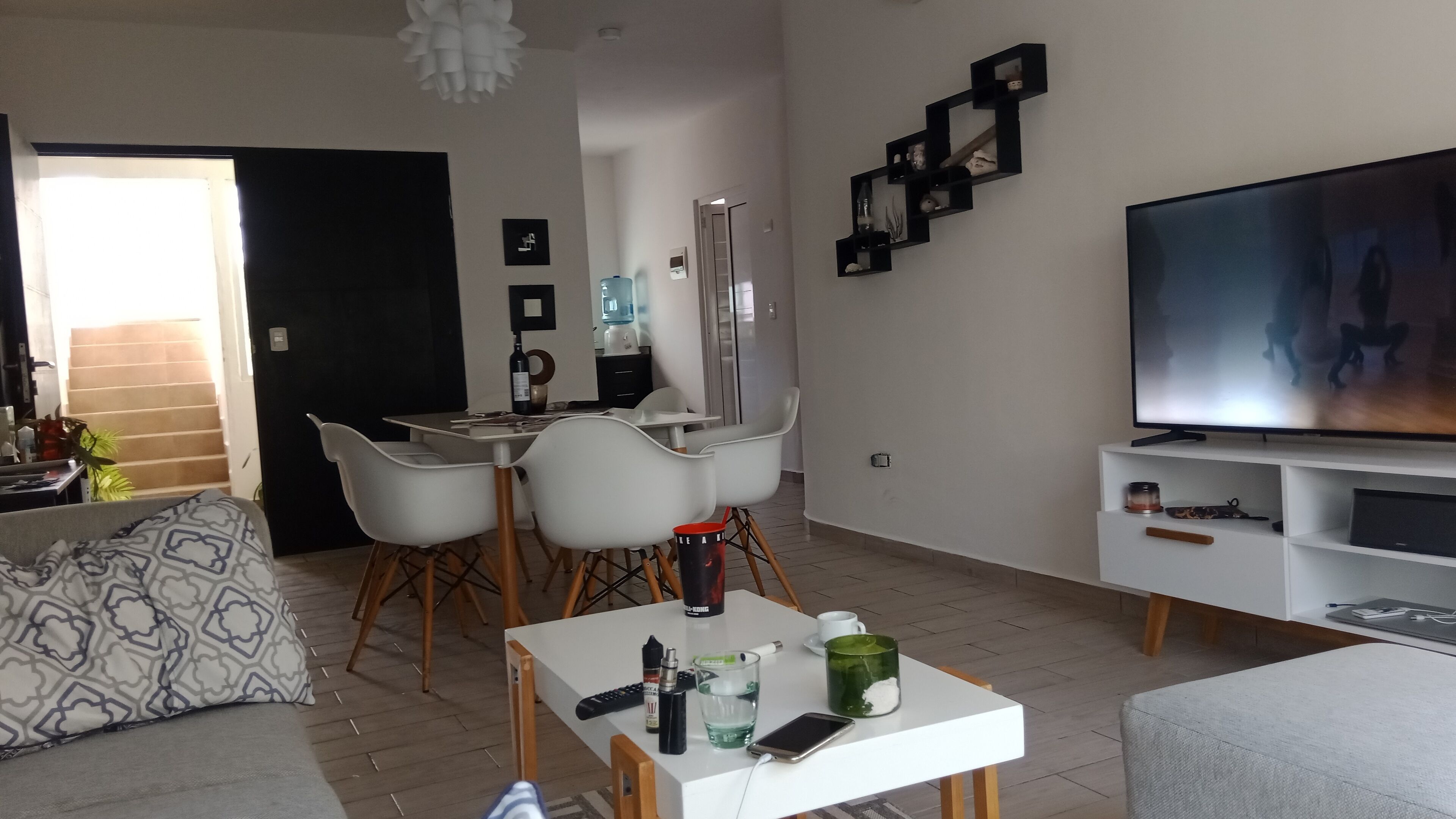 Un salon moderne comprenant un coin repas, un téléviseur à écran plat et un escalier menant à un autre niveau.