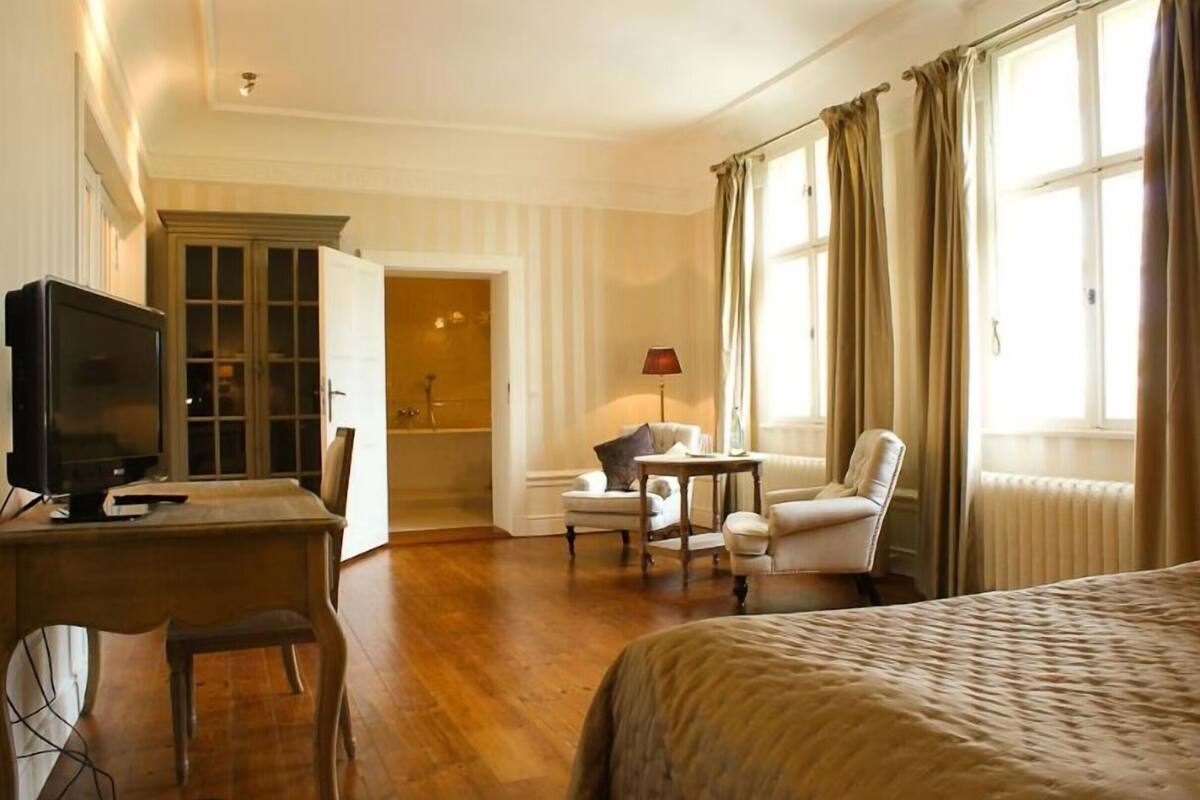 Ein Hotelzimmer mit Bett, Schreibtisch mit Fernseher, Stuhl, kleinem Tisch mit Lampe und angrenzendem Badezimmer.
