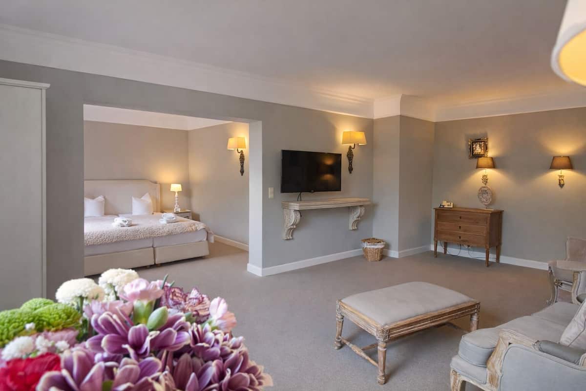 Ein Hotelzimmer mit einem Bett, einem an der Wand montierten Fernseher, einer Holzkommode, einem Sofa und einem kleinen Tisch.