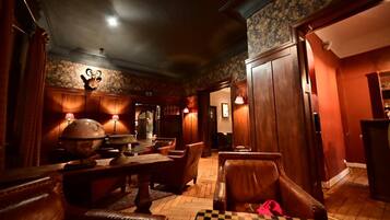 A dimly lit room with wooden furniture, a globe on a table, and a checkered table runner.