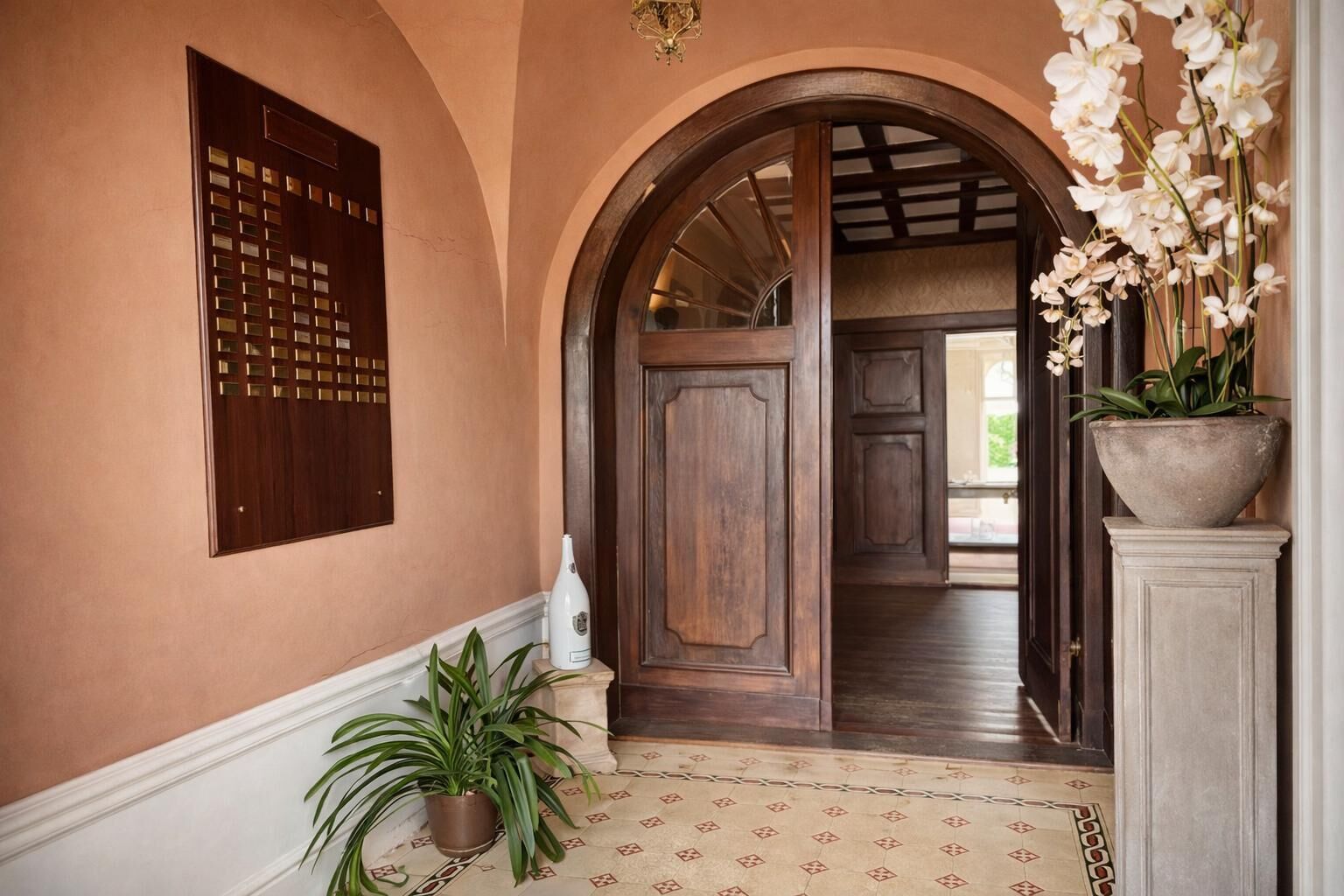 Un pasillo con puerta de madera, una planta en maceta y un panel decorativo en la pared.