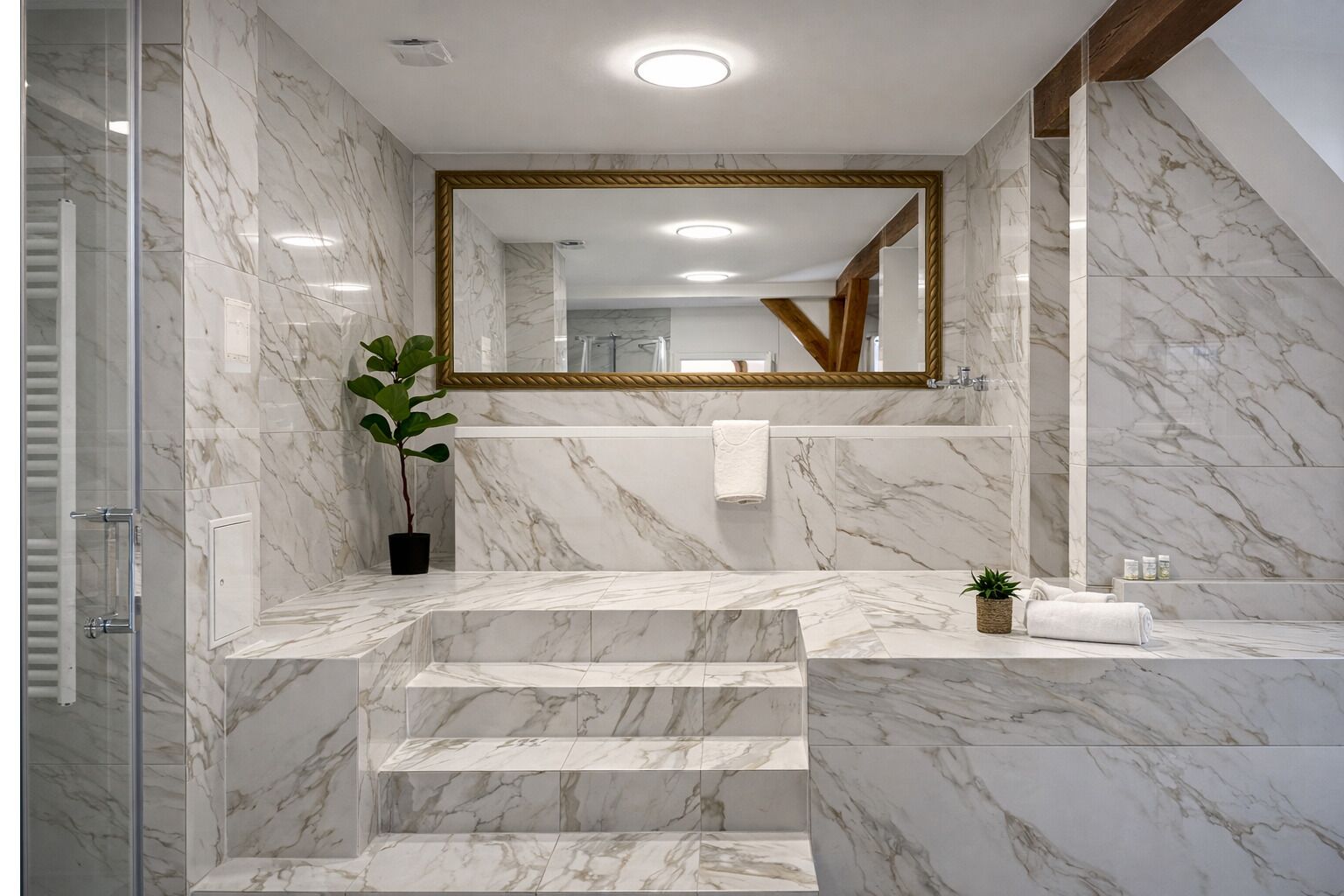 A modern bathroom with marble walls, a large mirror, and a staircase leading to a shower area.